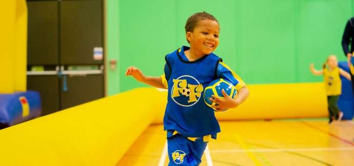 Young boy running holding a football.