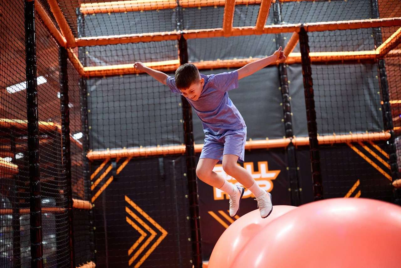 Young person jumping across giant balls inside the TAG Challenge Arena.