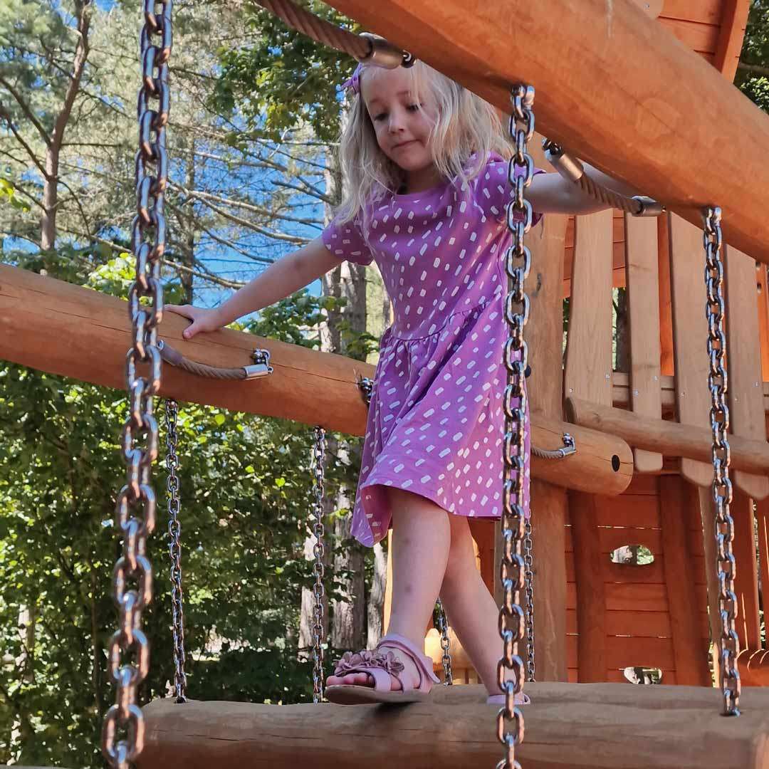 Young girl walking over a wooden bridge 