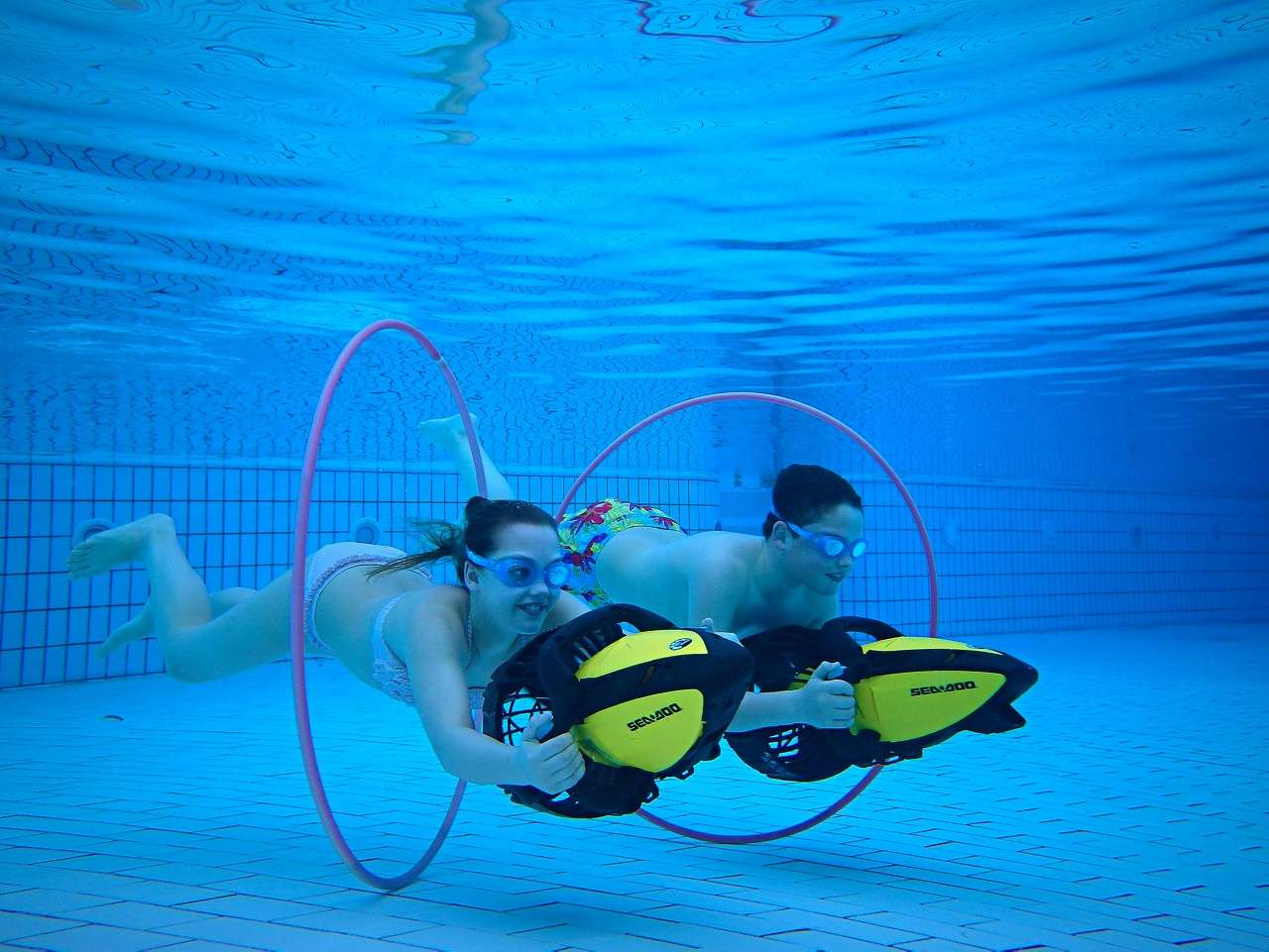 Two people swimming with submersible Seadoo.