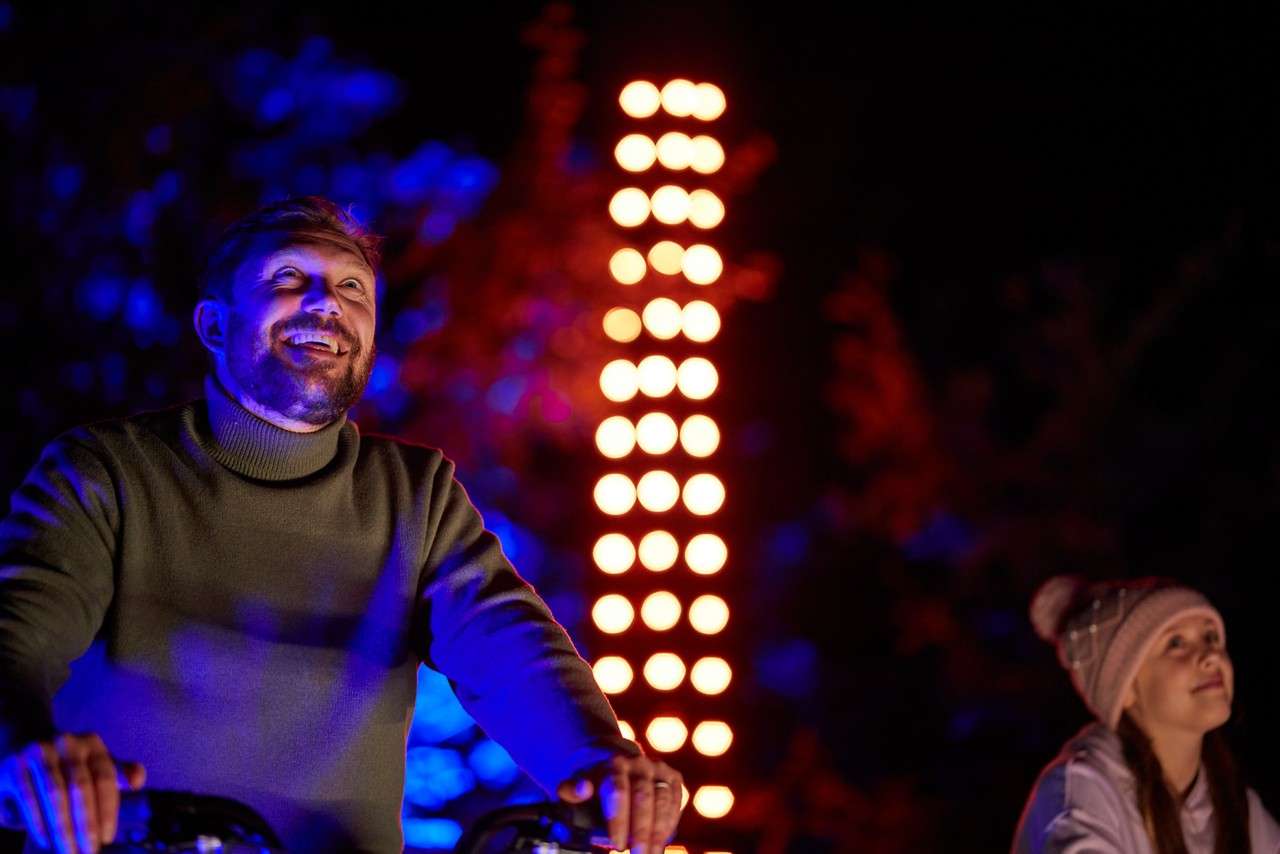 Family cycling to power lights in the forest.