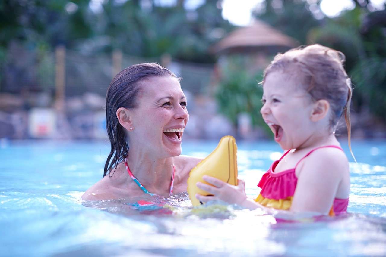 Young girl holding an inflatable doolphin with an adults supervision.
