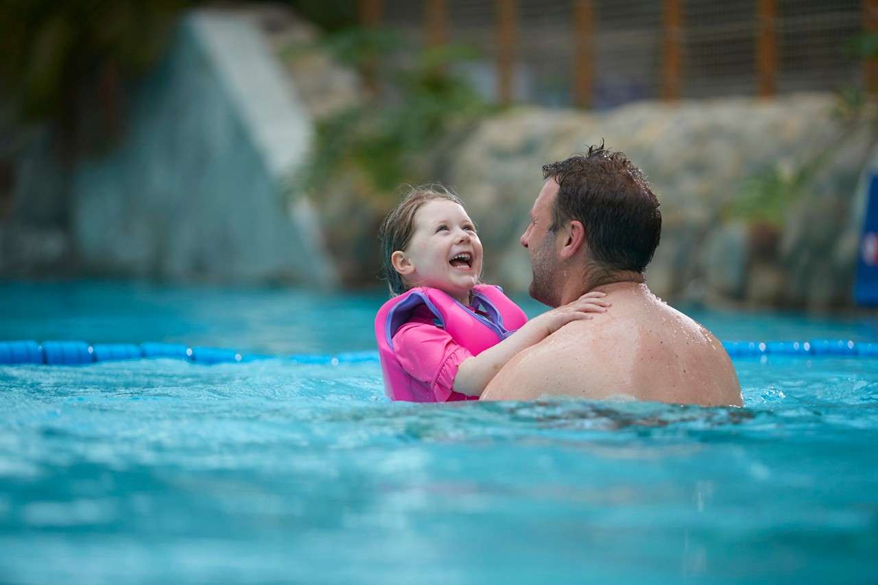 Young girl with an adult having fun in the Wave Pool.