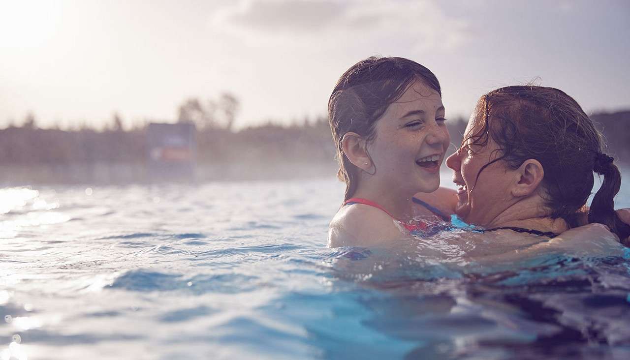 Woman with a young girl in an Outdoor Pool.