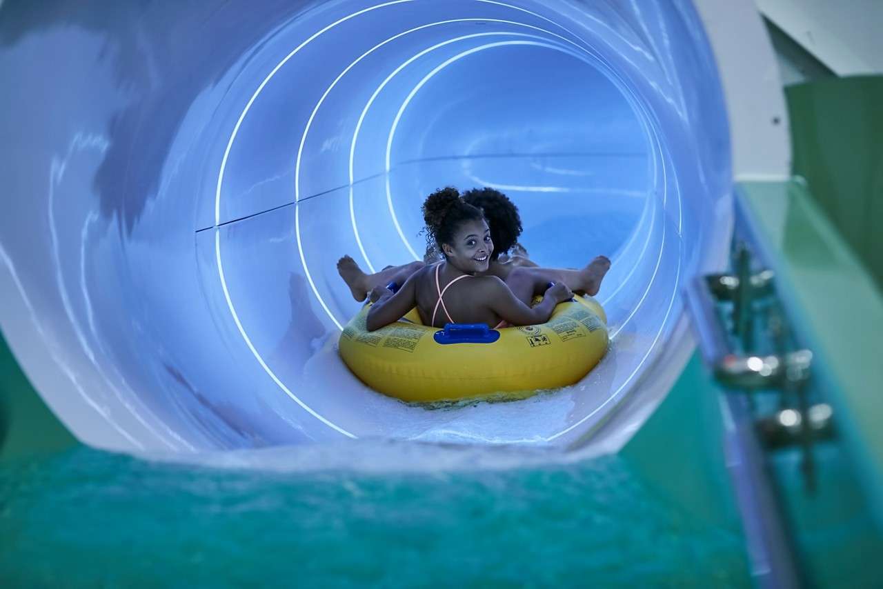 People sitting in an inflatable raft going down a water slide.