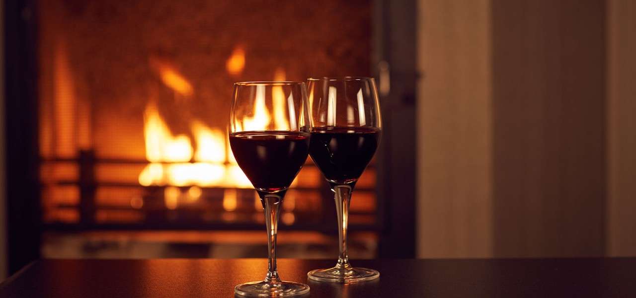 Two glasses of wine in front of an open fire 