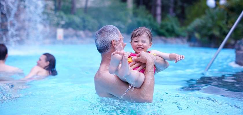 A grandfather playing with his granddaughter in the pool