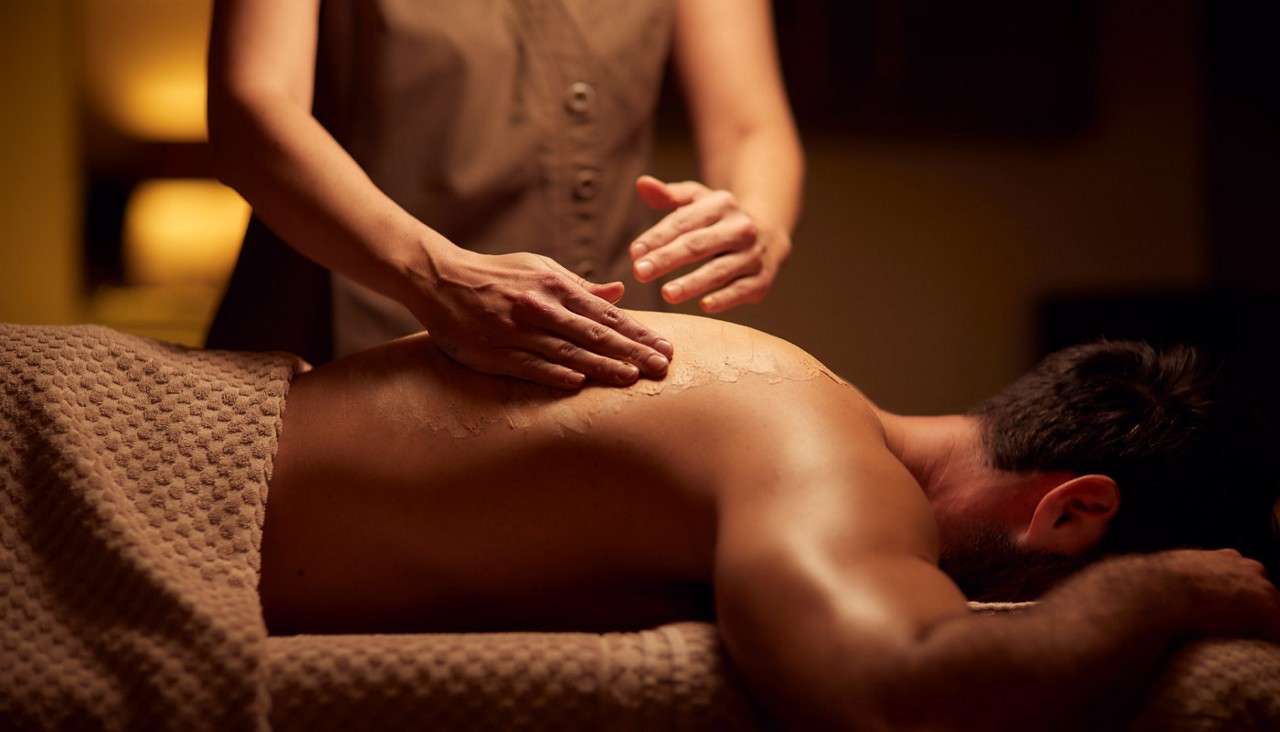 Spa therpist applying cream products to a mans back.