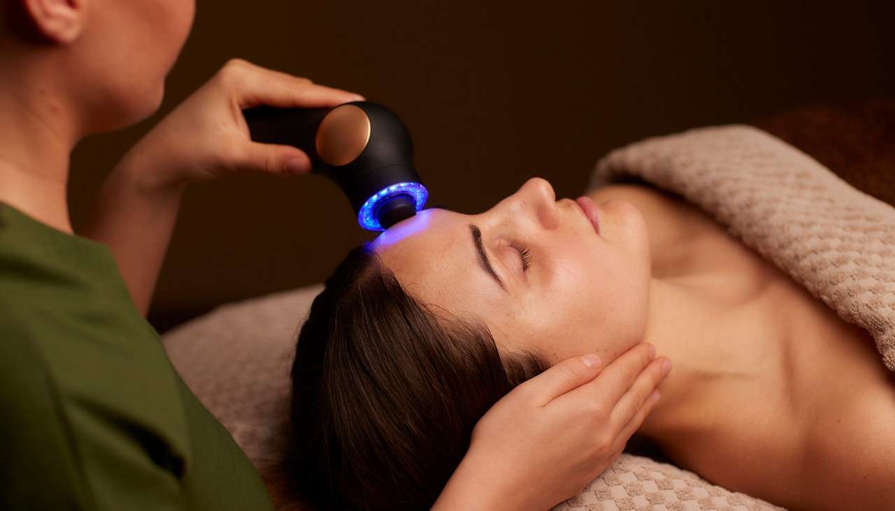 Woman having a facial with a microcurrent handheld device.