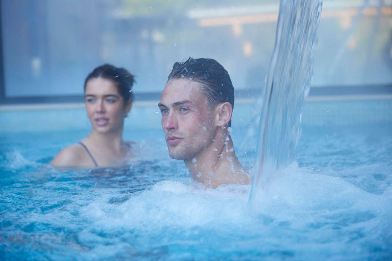 man under the water jet in the pool