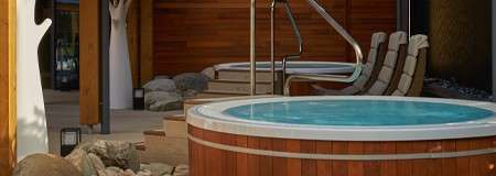 Outdoor hot tub surrounded by decorative garden pieces.