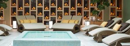 Shallow pool surrounded by lounge chairs and glowing candles.