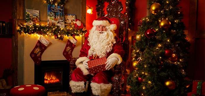 Santa sat next to a christmas tree