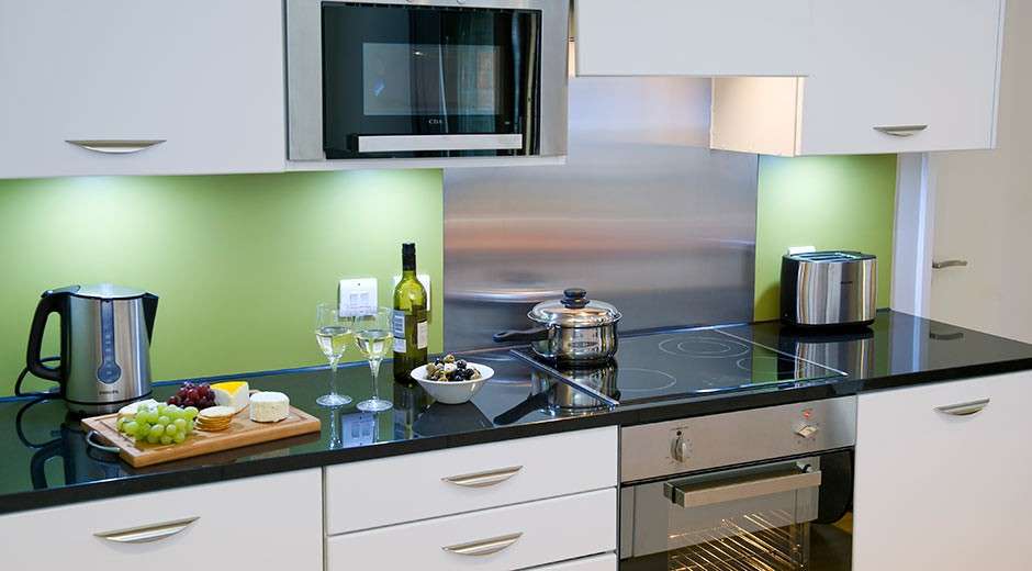 A woodland Lodge Kitchen area. There is a pan on the stove, a bottle of wine and glasses on the side as well as some snacks. 
