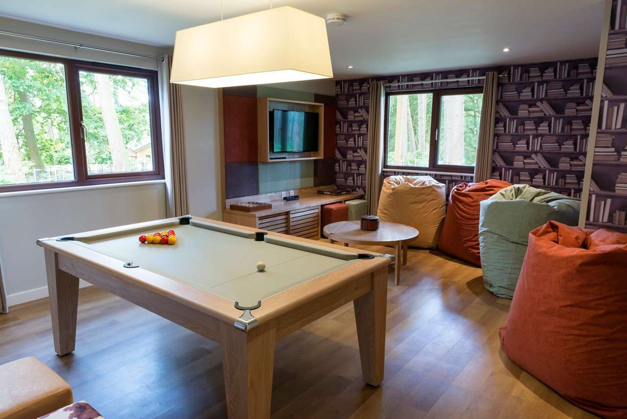A pool table and TV in a games room. 