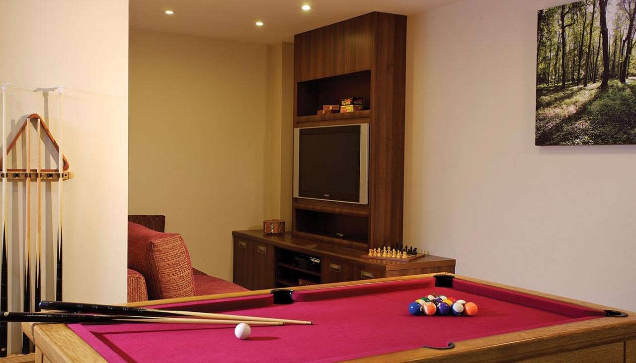 A pool table and TV in a games room. 
