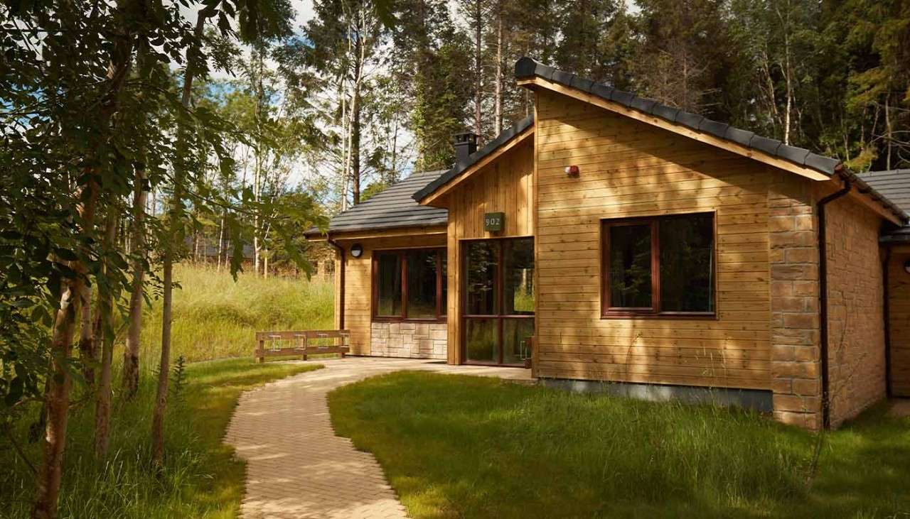 Exterior view of a Woodland Lodge, covered slightly by the sun's shade.