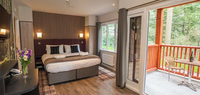 The interior of a Pinewood apartment with a bed in a bedroom next to a balcony