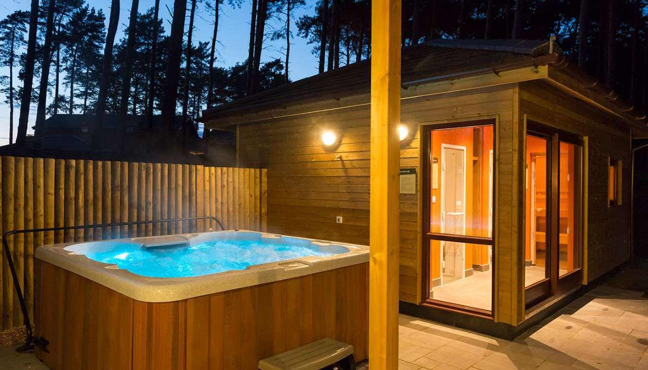 A hot tub  and steam room lit up outdoors at dusk