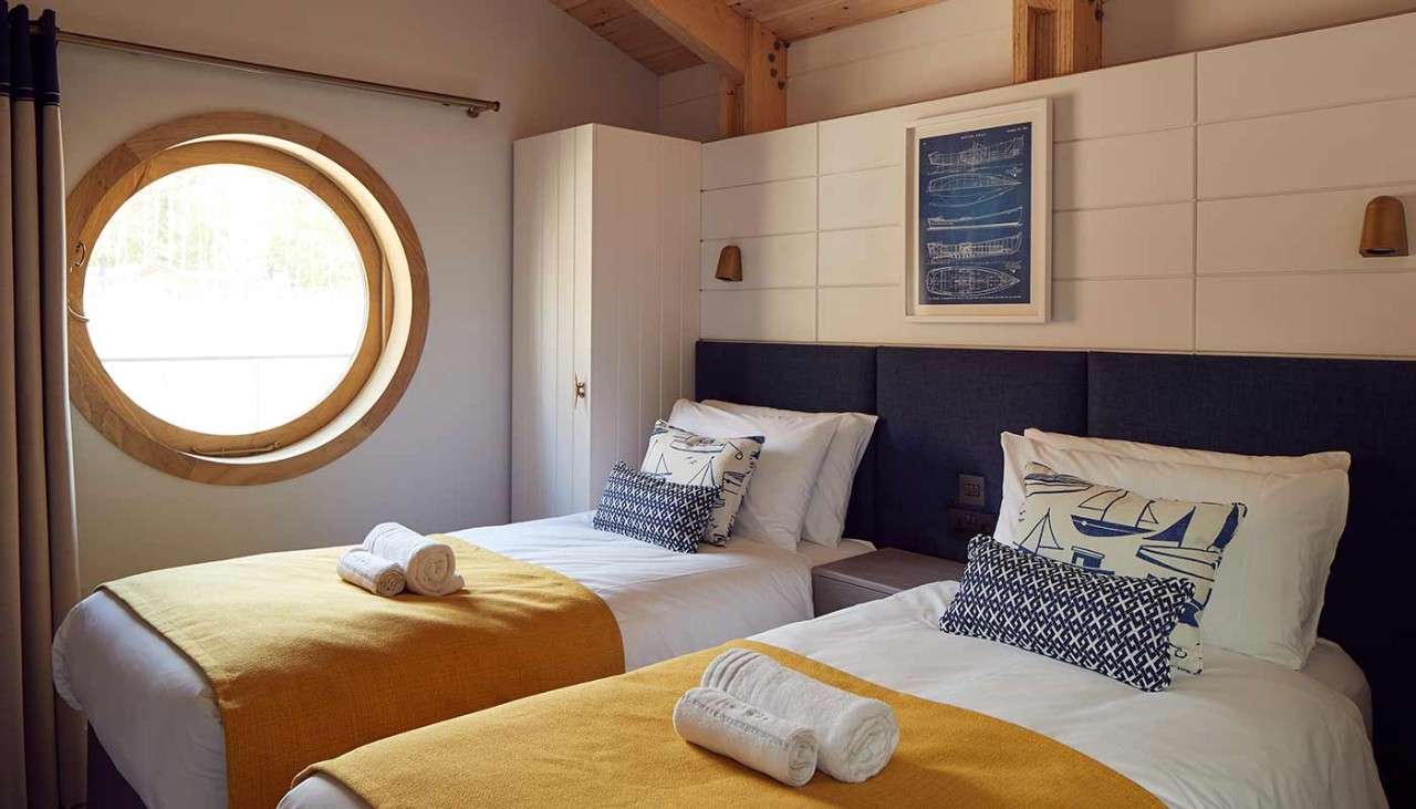 Neatly made twin beds in a bedroom in a Waterside Lodge 
