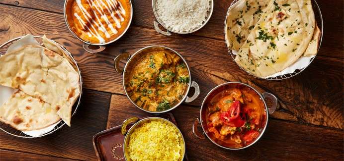 A table full of Indian dishes including, rice, naan bread and a selection of curries