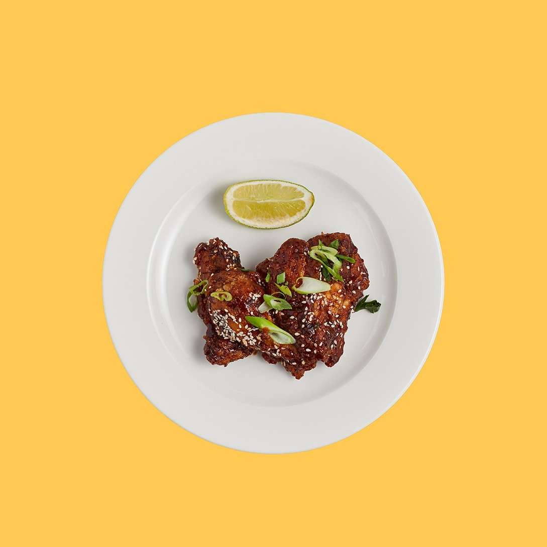 Chicken wings topped with chopped spring onions and sesame seeds served with a slice of lime.