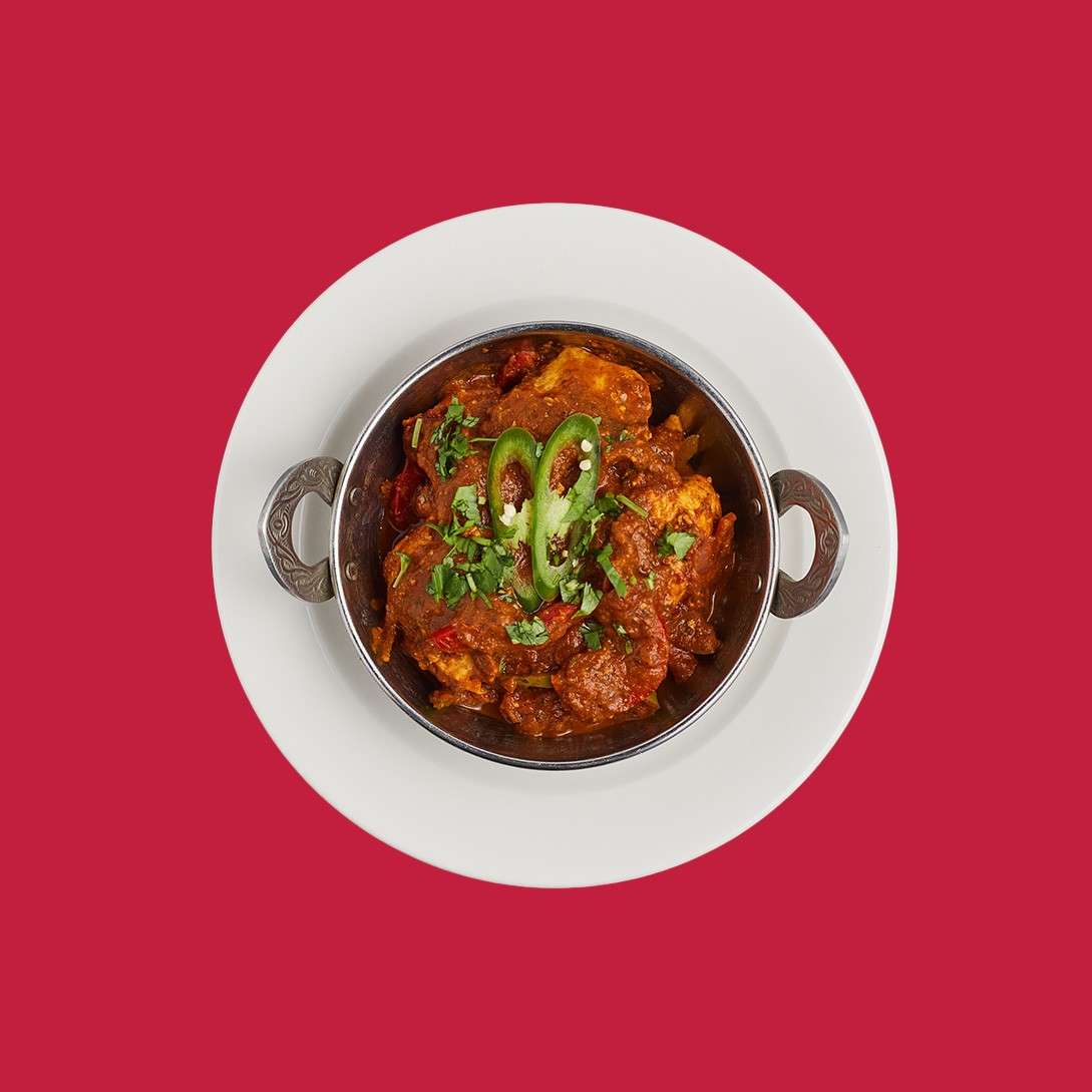 Chicken jalfrezi served with sliced chilli in a traditional bowl.