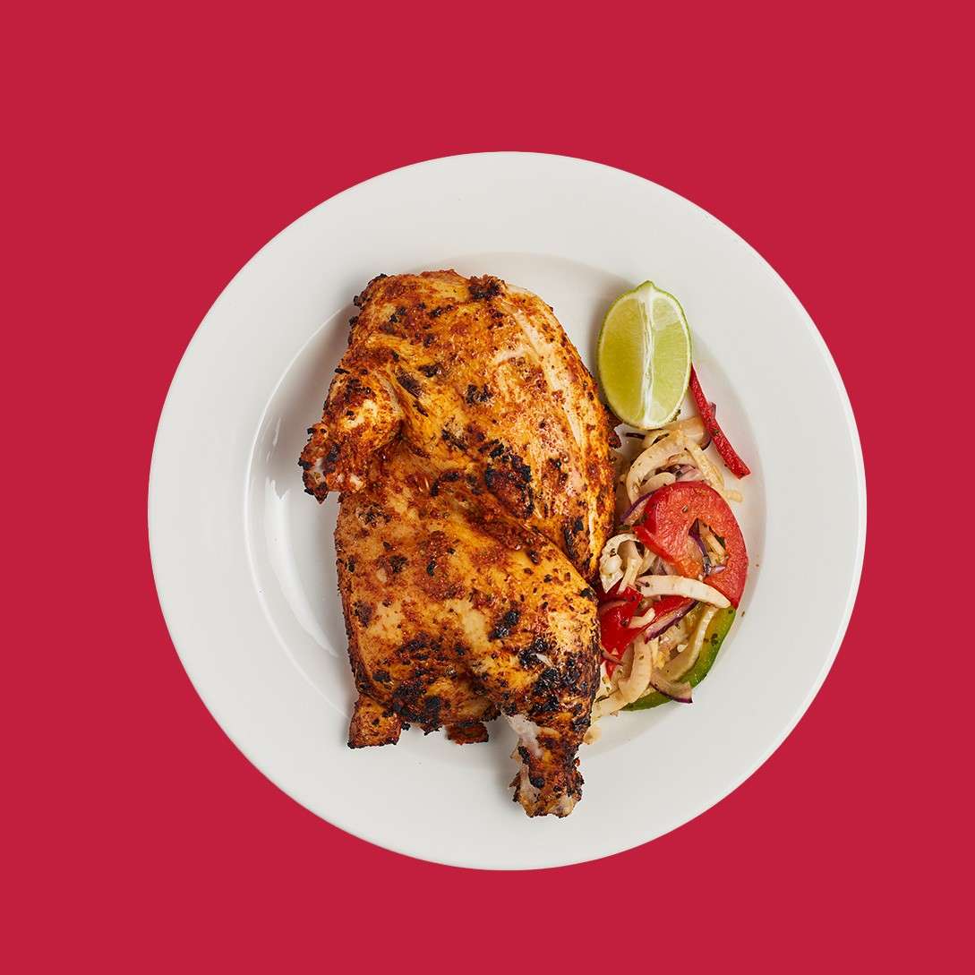 Tandoori half chicken served with small vegetable salad and a slice of lime.