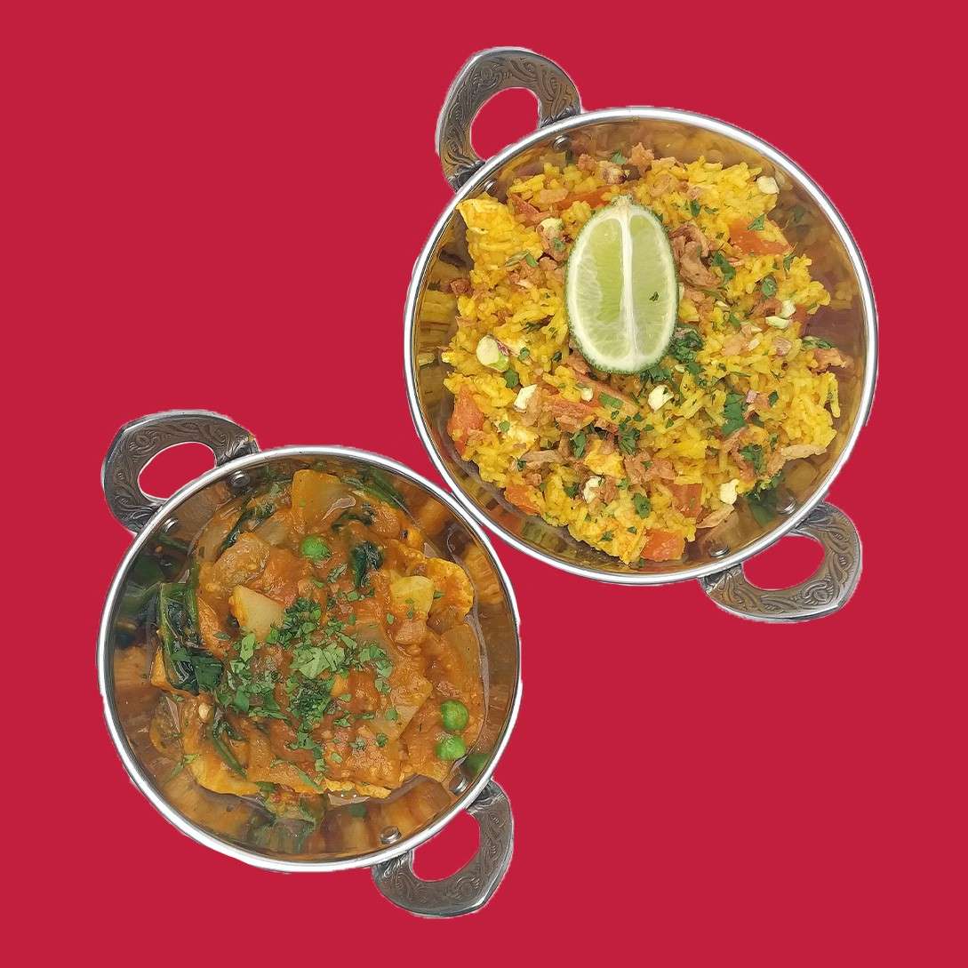 Two metal bowls present Indian dishes: one holds yellow rice pilaf topped with a lime wedge; the other contains vegetable curry with peas and herbs, set against a red background.