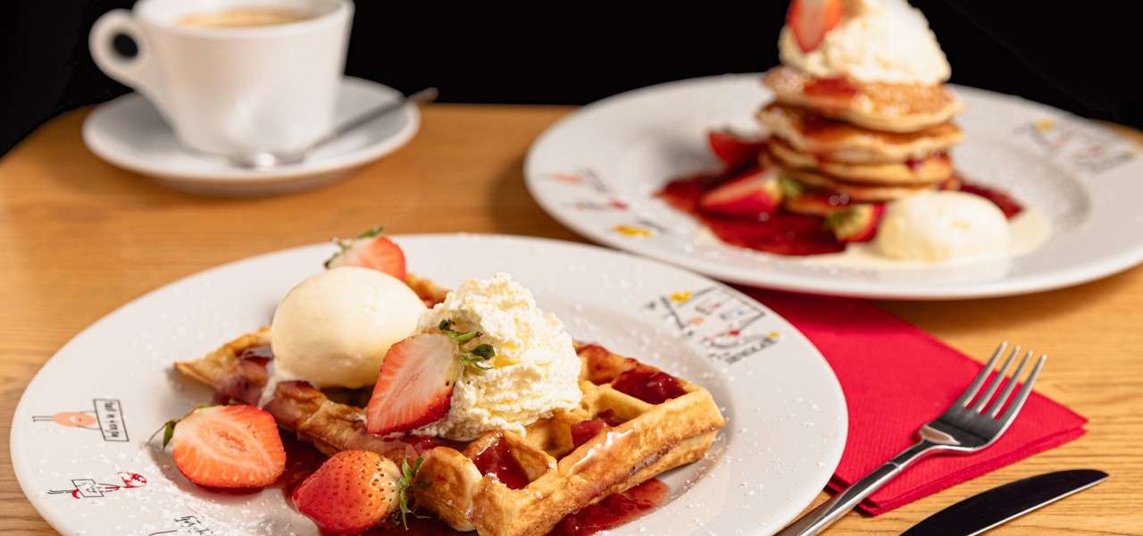 Waffle topped with strawberries and ice cream.