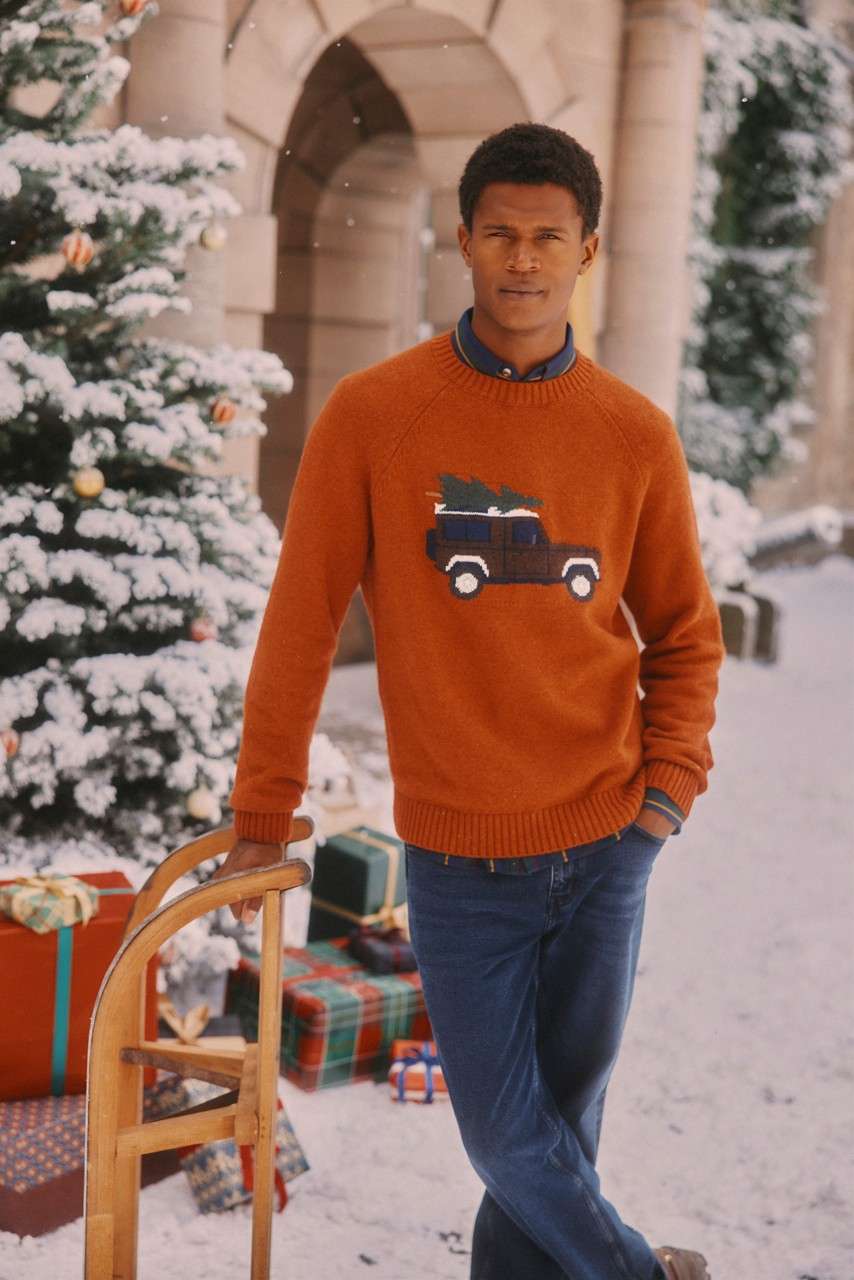 Man wearing a Christmas jumper and jeans.