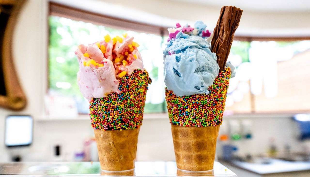 Two ice creams topped with sprinkles and a flake.