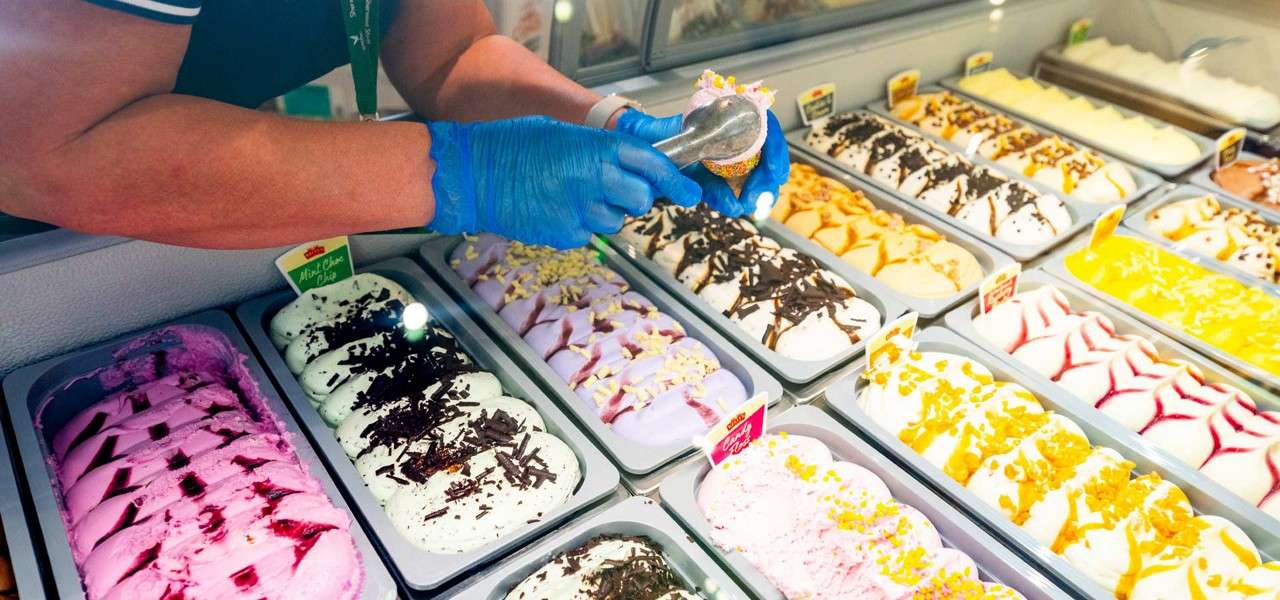 Staff member scooping colourful ice cream.