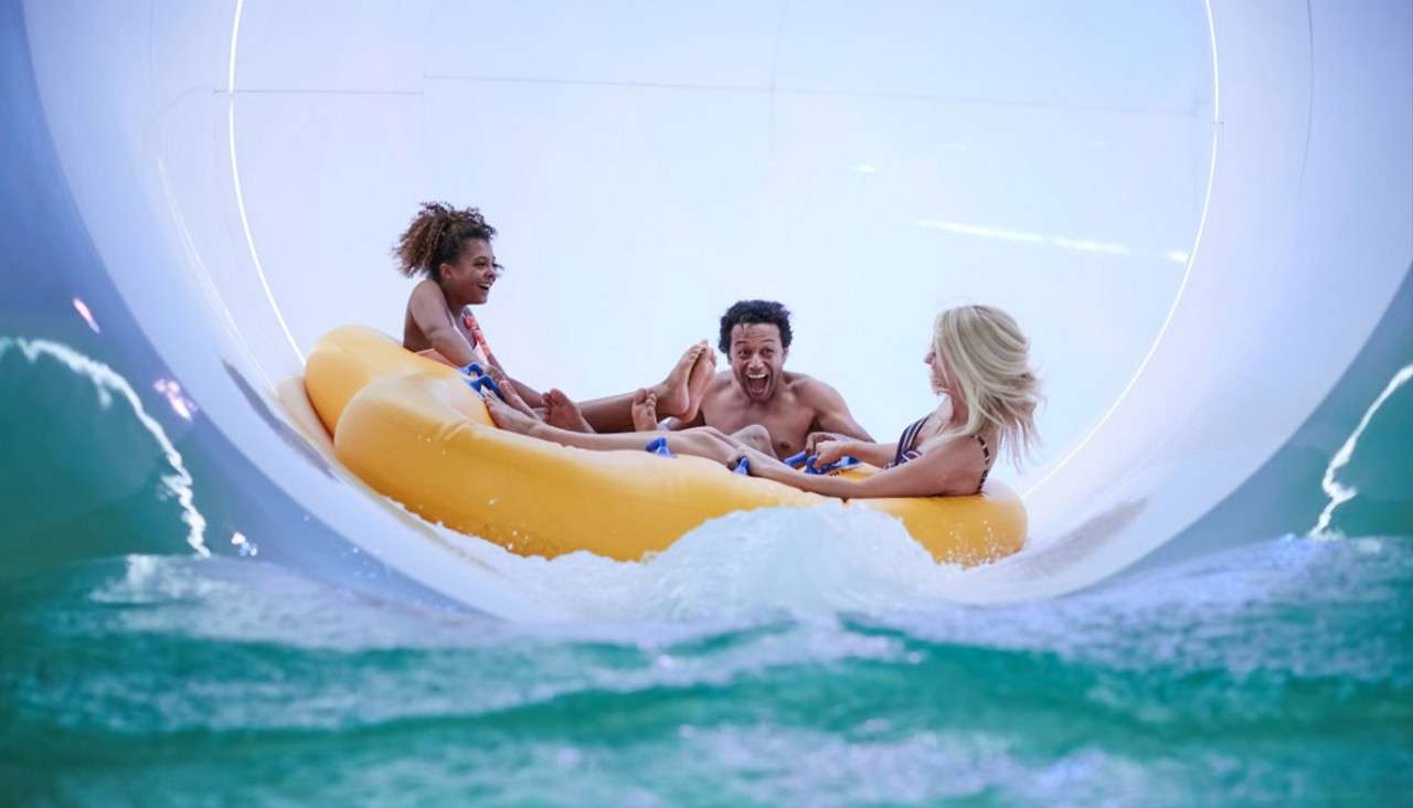 Three young adults sliding down the Tropical Cyclone water slide.