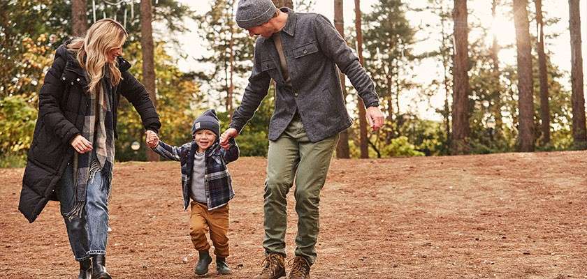 A family holding hands and walking around an autumnal forest.