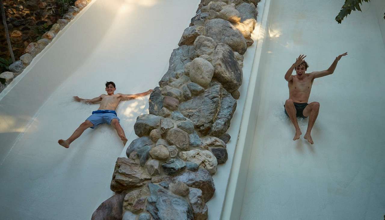 Two teenagers sliding down a waterslide.
