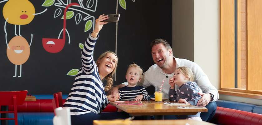 A family taking a selfie together at a table in the Pancake House.
