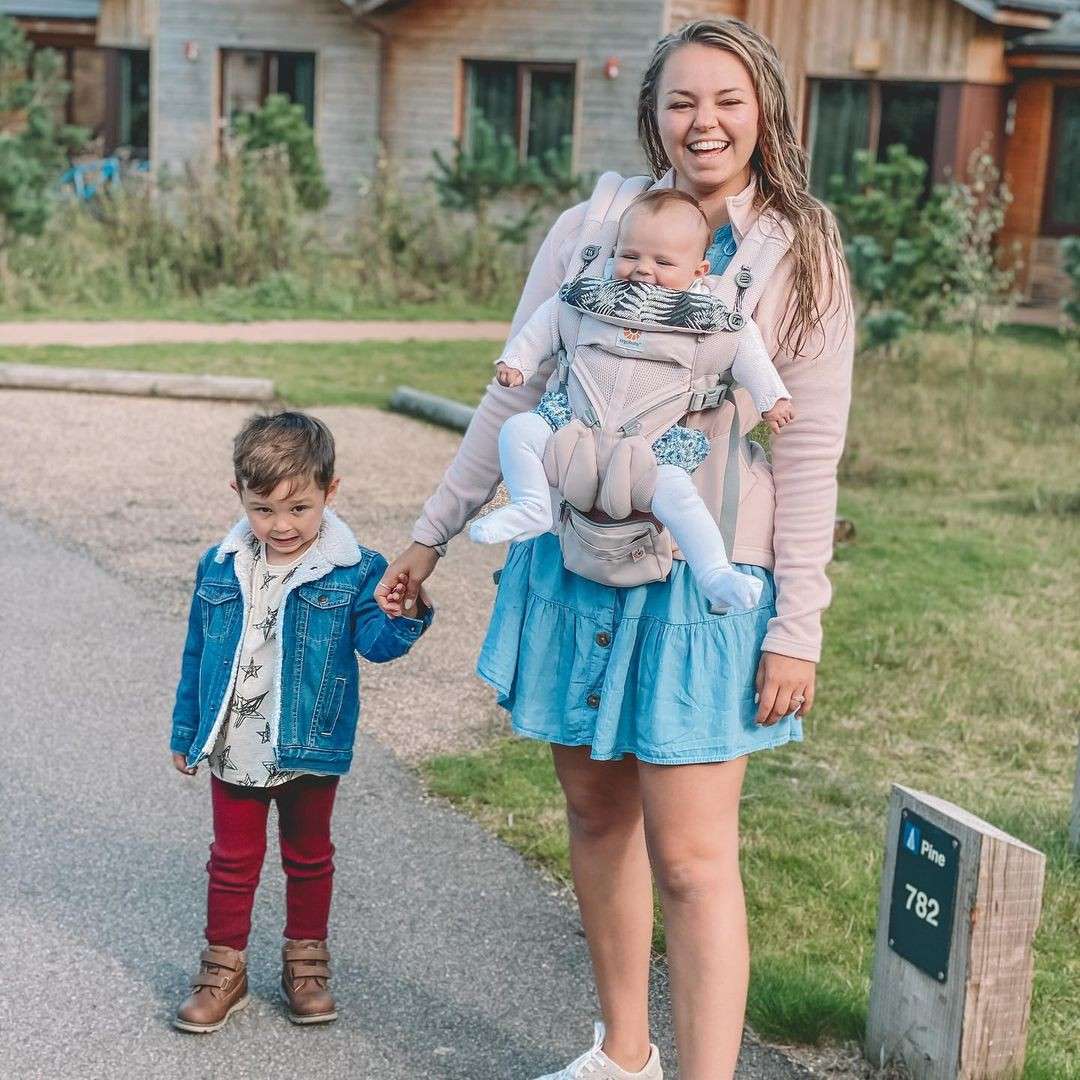 A mother and her two young children standing outside of the lodges
