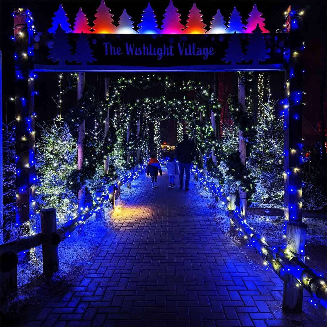 A boy walking through The Wishlight Village with his father.