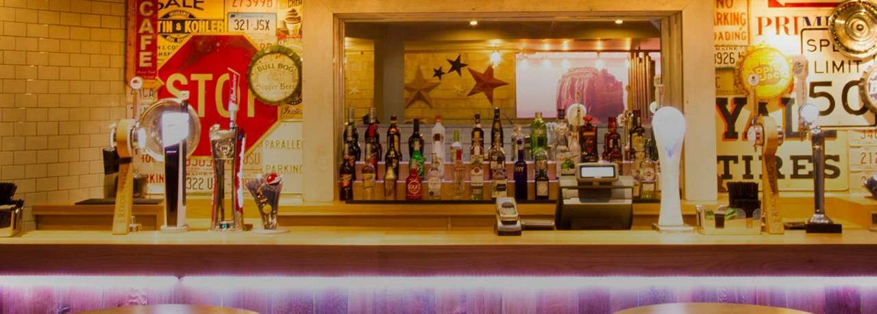 A bar with taps of beer and spirits in the background