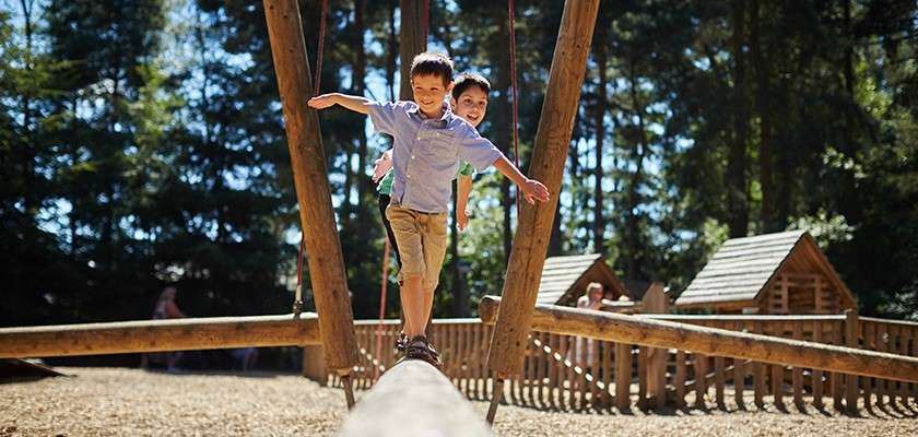 Boys playing on a wooden climbing frame 