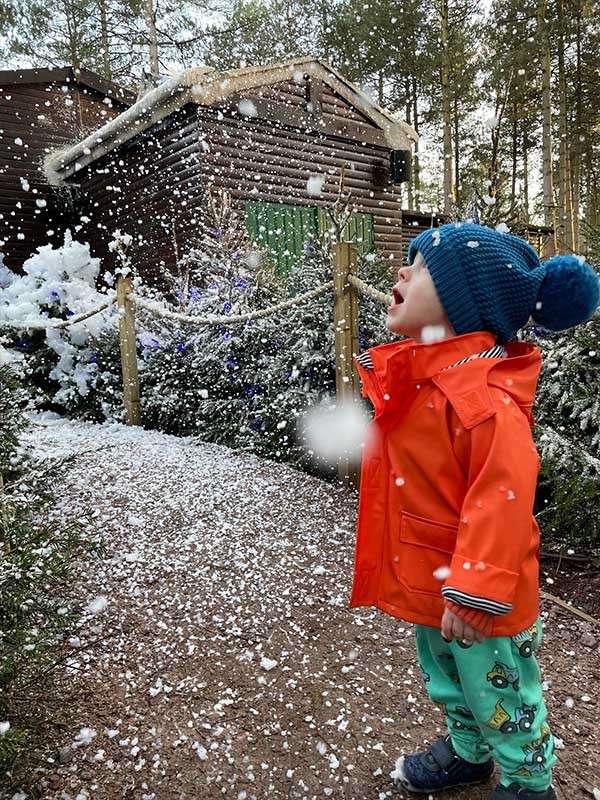 A little boy looking up at the falling snow. 