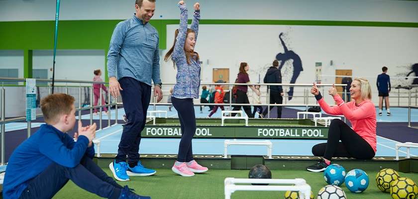 A family standing on a football pool indoor court.