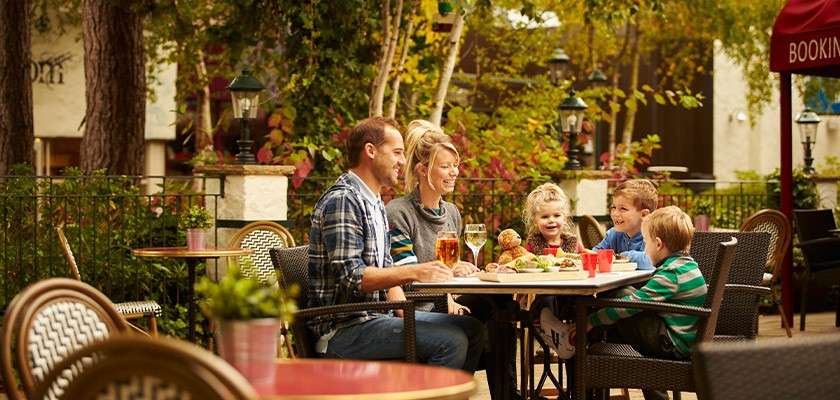 A family eating a meal sat around an outdoor table at a restaurant.