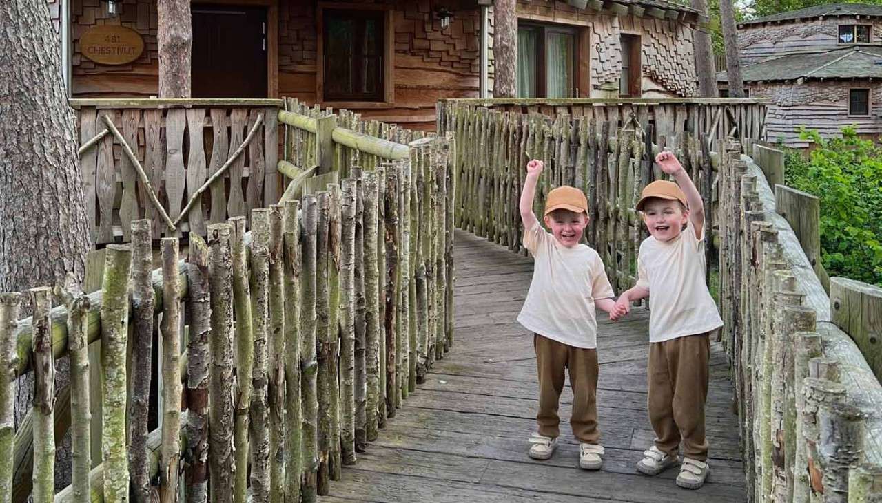 Two small toddlers holding hands on the entrance to their Treehouse.