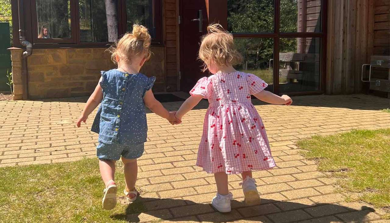 Two sisters holding hands in front of their lodge.