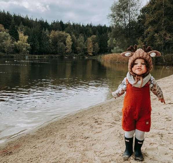 A little girl wearing a reindeer hat stood on the beach 