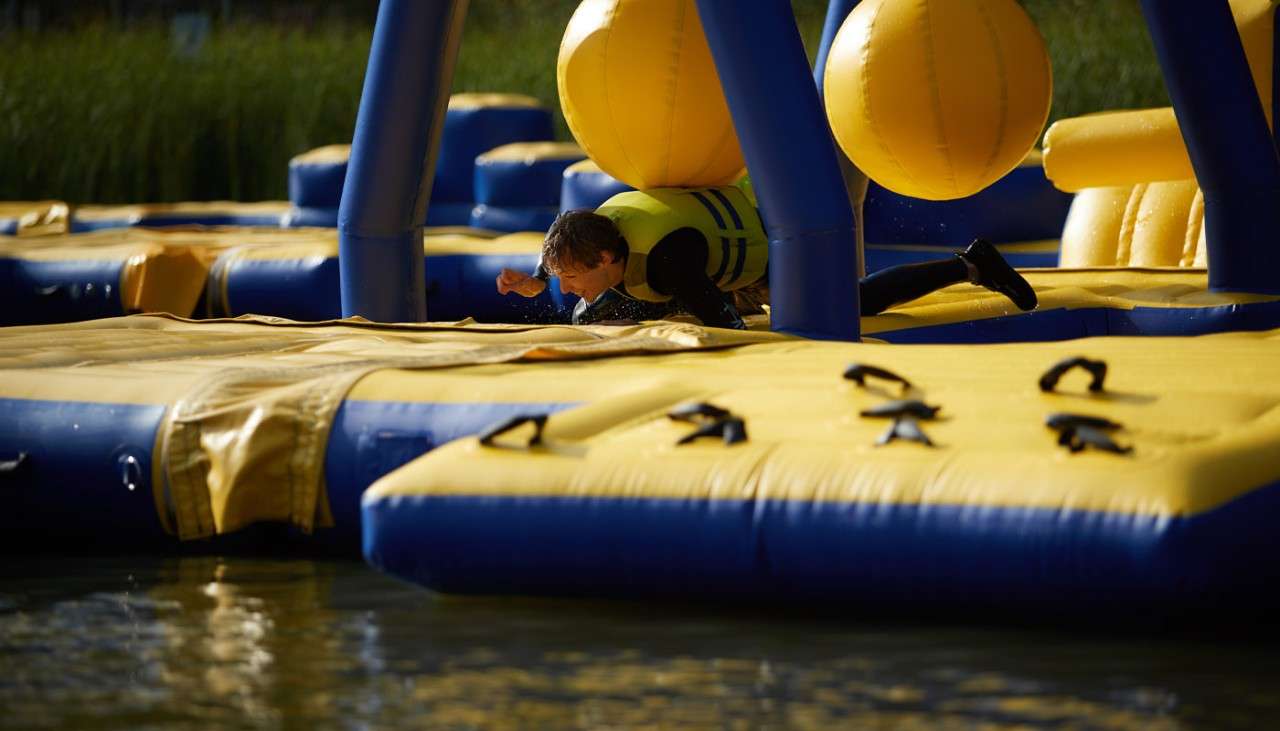 Person squeezing under a giant inflatable on the lake.