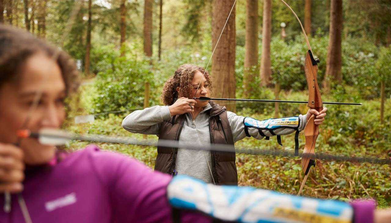 Two women aiming a bow and arrow