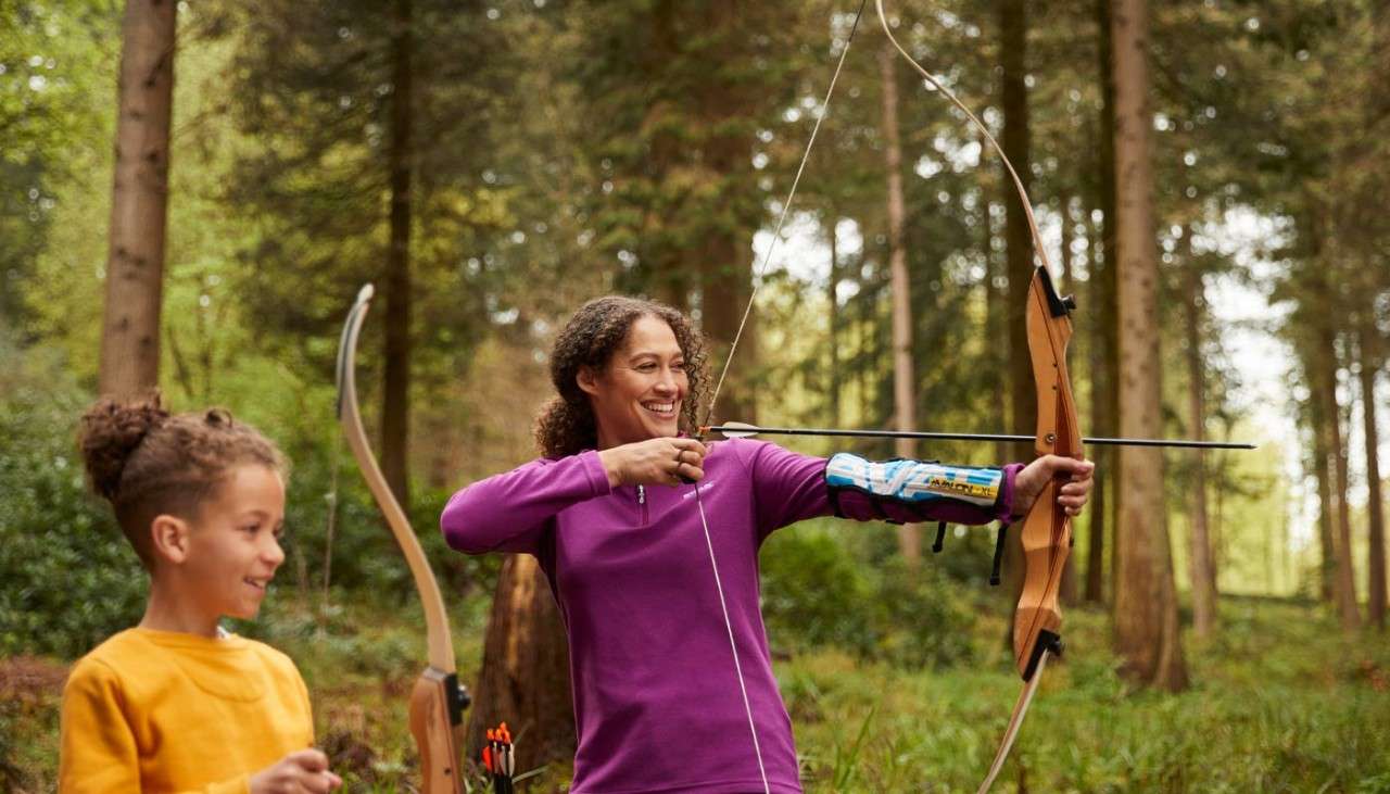 Boy watching woman shoot a bow and arrow